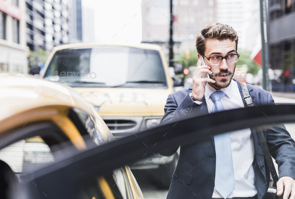 USA, New York City, businessman in Manhattan on cell phone entering a taxi
