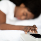 Black woman laying in bed, turning off alarm on cellphone - PhotoDune Item for Sale