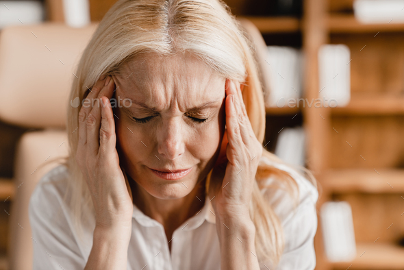 Businesswoman rubbing temples suffering from headache, depression, overworked, migraine, coronavirus - Stock Photo - Images