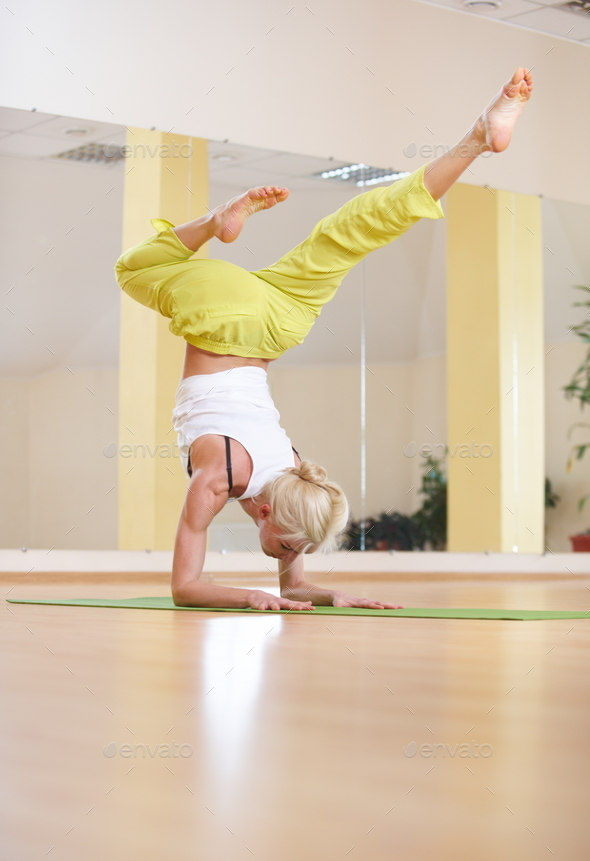 Beautiful sporty fit yogi woman practices yoga asana Vrischikasana Scorpion pose in the fitness room