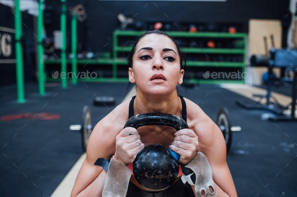 Young woman training swinging kettlebell indoor in a crossfit gym