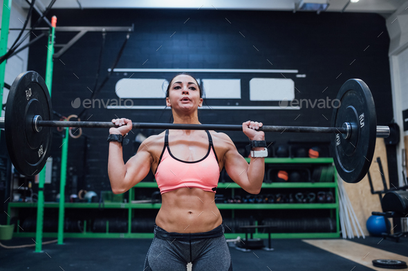 Young woman power lifting training indoor gym alone