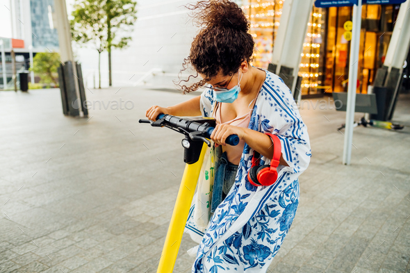 Young mixed woman riding electric scooter outdoors