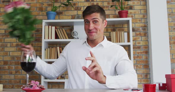 Caucasian man making video call presenting bunch of flowers blowing kiss and smiling alt