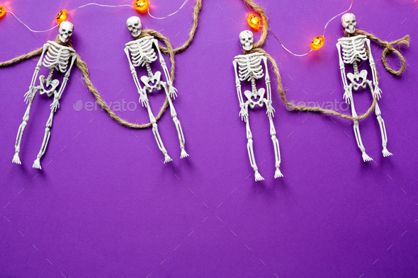 Halloween layout of garland of skeletons on a rope, glowing Jack o Lantern, pumpkins