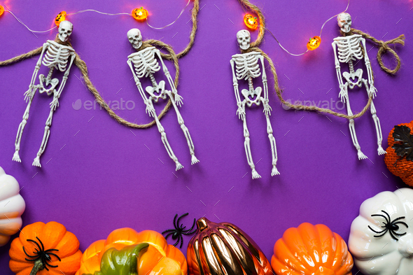 Halloween layout of garland of skeletons on a rope, glowing Jack o Latern, pumpkin