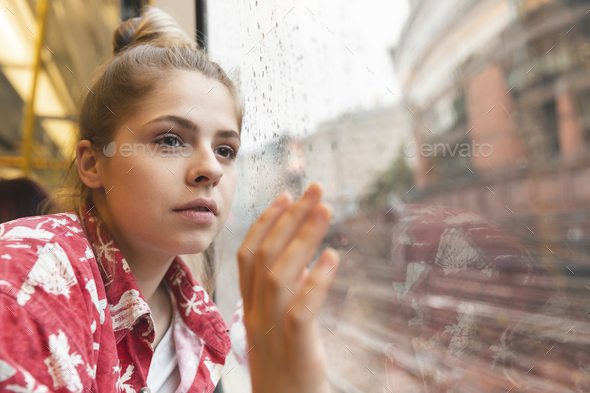 Young woman travelling by train and looking out of the window - Stock Photo - Images