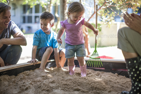 Girl with family playing in sandpit
