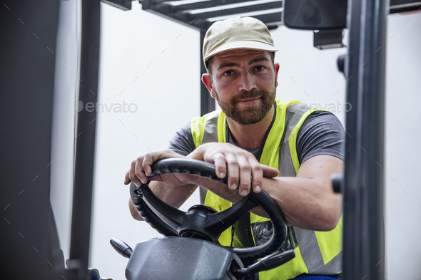 Portrait of confident man on forklift - Stock Photo - Images