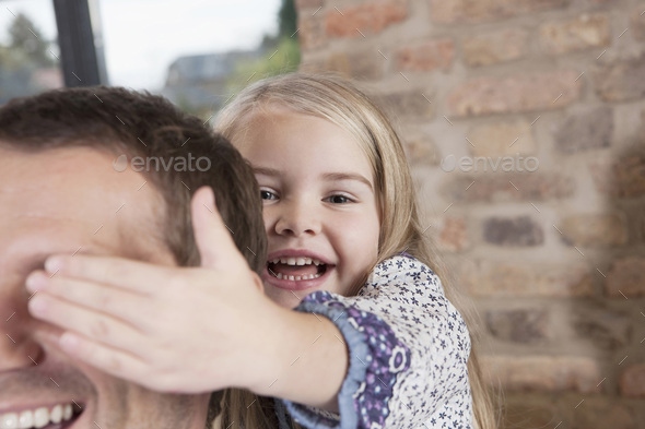 Germany, Cologne, Girl (6-7) covering father\'s eyes, portrait, close-up