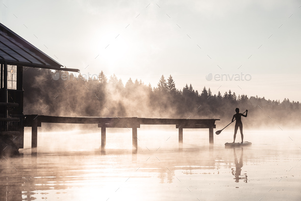 Silhouette of a woman stand up paddling on lake Kirchsee at morning mist, Bad Toelz, Bavaria, German