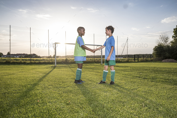 Young football players shaking hands on football ground