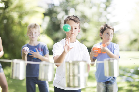 Boy trying to throw balls into tin can - Stock Photo - Images