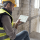 Caucasian engineer sitting on stairs and holding digital tablet on construction site - PhotoDune Item for Sale