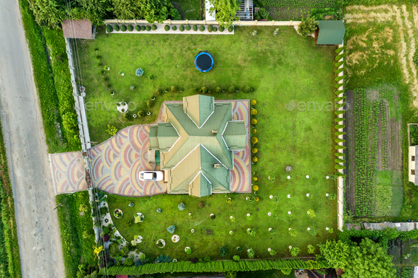 Aerial top view of house shingle roof and a car on paved yard with green grass lawn