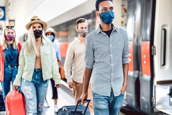 Crowd of people walking at railroad station platform covered by protective face mask