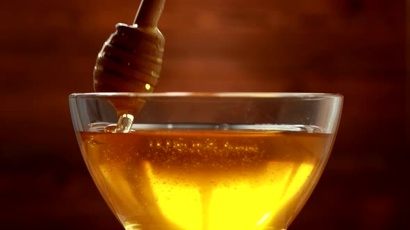 Dense Bee Honey of Golden Color in a Transparent Bowl on a Wooden Background alt