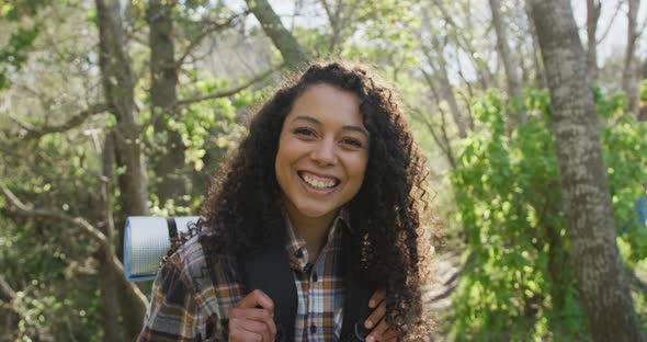 Portrait of smiling biracial woman in forest during hiking in countryside alt