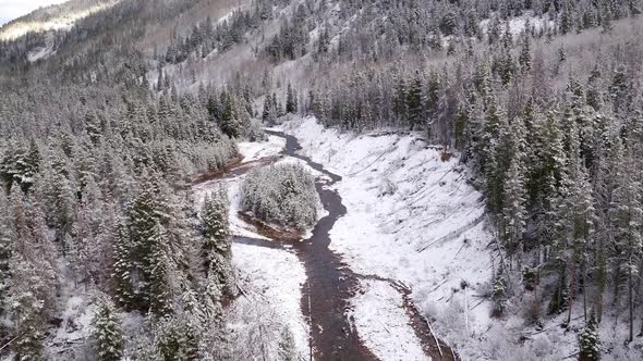 Aerial view flying over river flowing through snow covered landscape alt