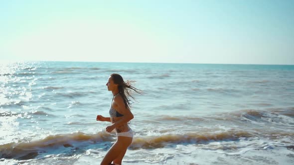 Happy Young Stunning Woman with Beautiful Slender Body is Engaged in Gymnastics at Sea at Sunrise alt