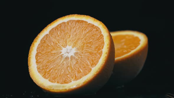 Half of a Juicy Orange Rotates in a Circle on a Black Background alt