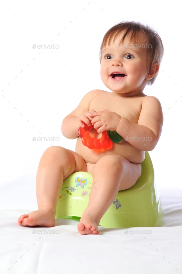 Pretty baby child sits on potty and holds teether