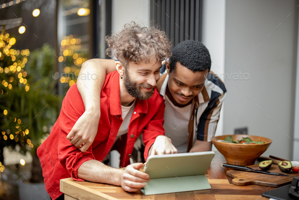 Two guys watching movie together on digital tablet at home