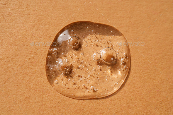 A drop of cosmetic gel on a beige background.