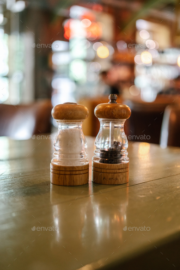 The salt and pepper shakers are on the table in a bar or cafe.