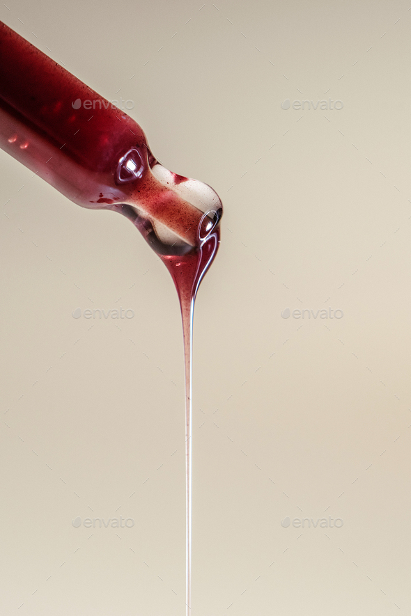 A drop of red serum drops from the pipette