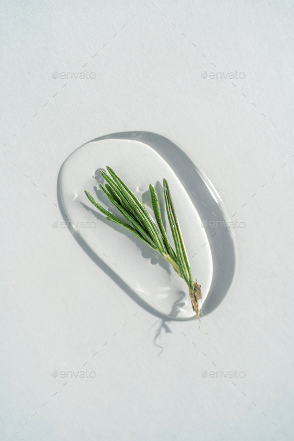 A drop of cosmetic gel with rosemary on a blue background.