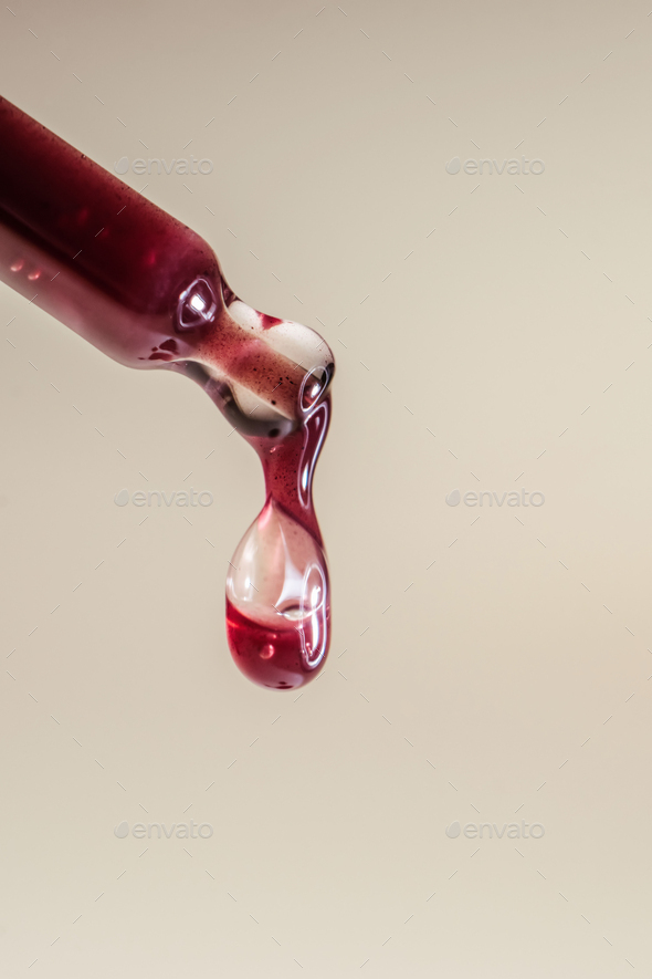 A drop of red serum drops from the pipette