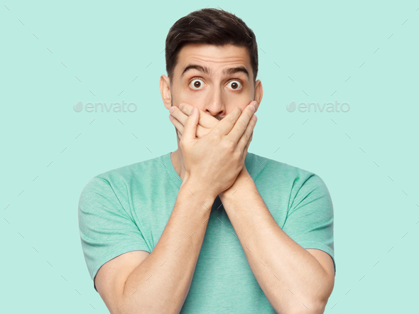 Shocked man covering mouth with both hands, eyes round with shock and fear