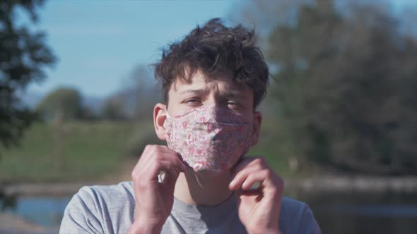 Young man puts on homemade flower pattern corona virus cotton mask MID SHOT alt