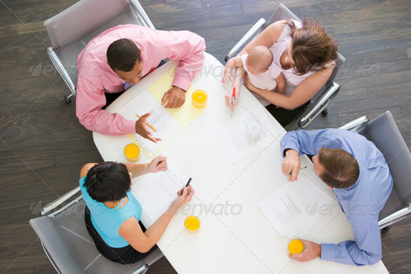 Four businesspeople in boardroom with one holding a baby - Stock Photo - Images