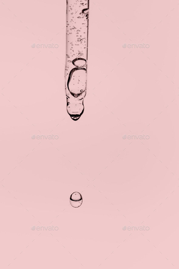 Transparent pipette with cosmetics on a pink background.