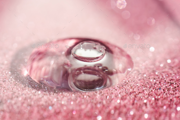 A drop of cosmetic gel on a pink shining background.