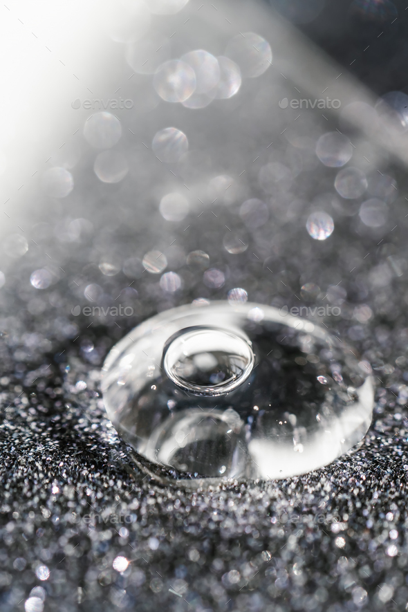 A drop of cosmetic gel on a black shining background.