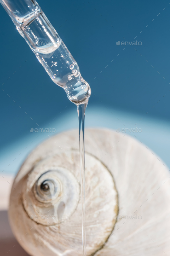 Pipette with transparent serum on the background of shells.