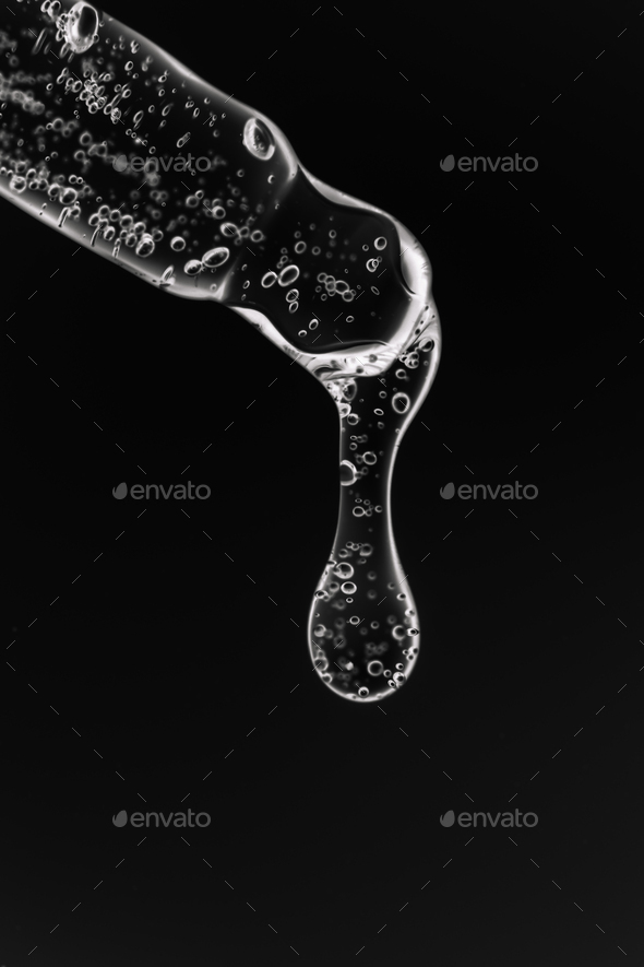Transparent pipette with cosmetics on a black background.