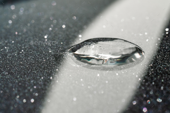 A drop of cosmetic gel on a black shining background.