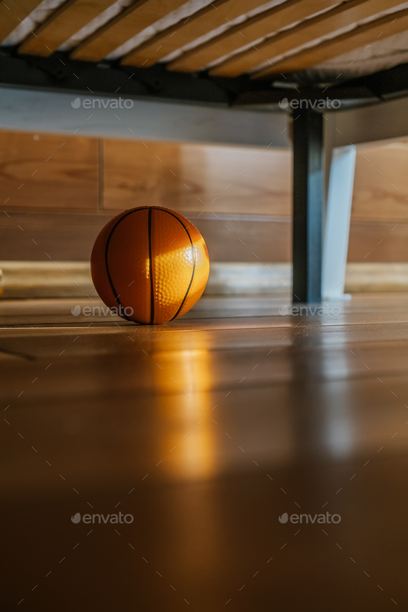 A children\'s basketball under the bed in the sun.