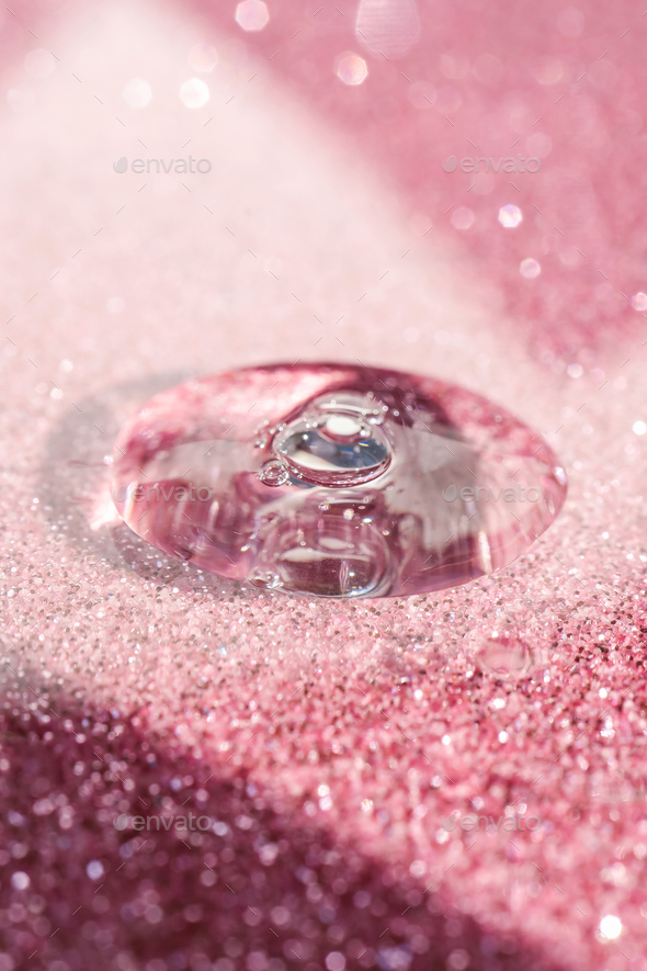 A drop of cosmetic gel on a pink shining background.