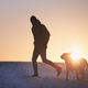 Man with dog running in snow at sunrise - PhotoDune Item for Sale