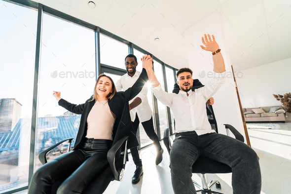 Happy multiracial IT workers ride chairs in the office