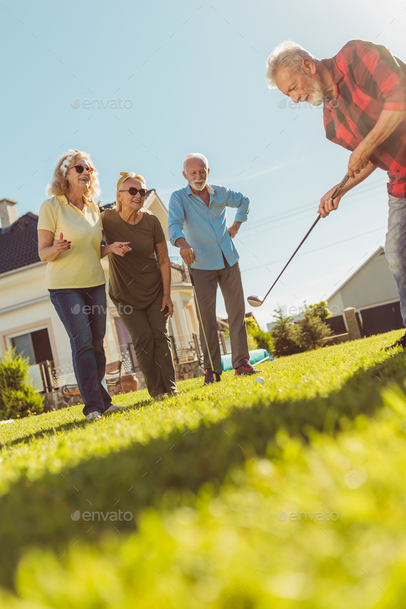 Elderly people playing golf on the backyard lawn
