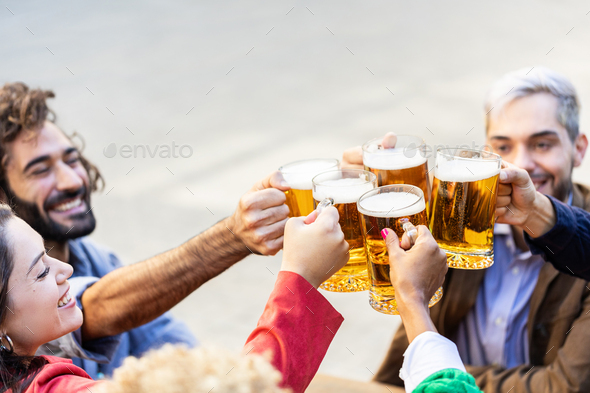 Group of multiracial friends cheering with beers in terrace bar