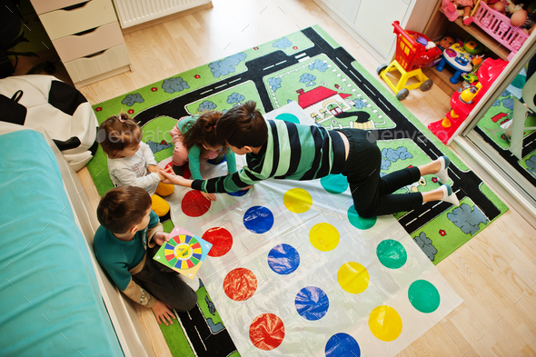 Happy family having fun together,four kids playing twister game at home.