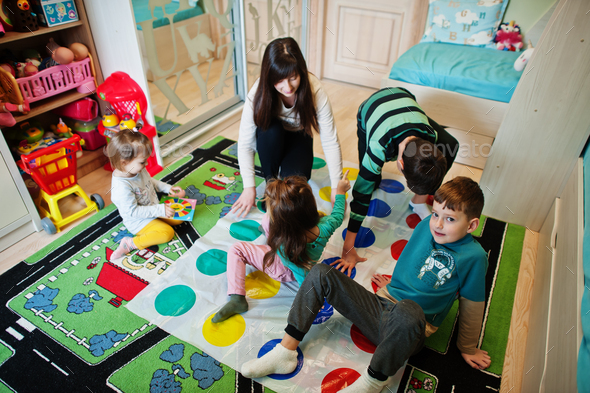 Happy family having fun together,four kids and mother playing twister game at home.