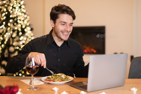 Excited man having dinner during virtual date on laptop
